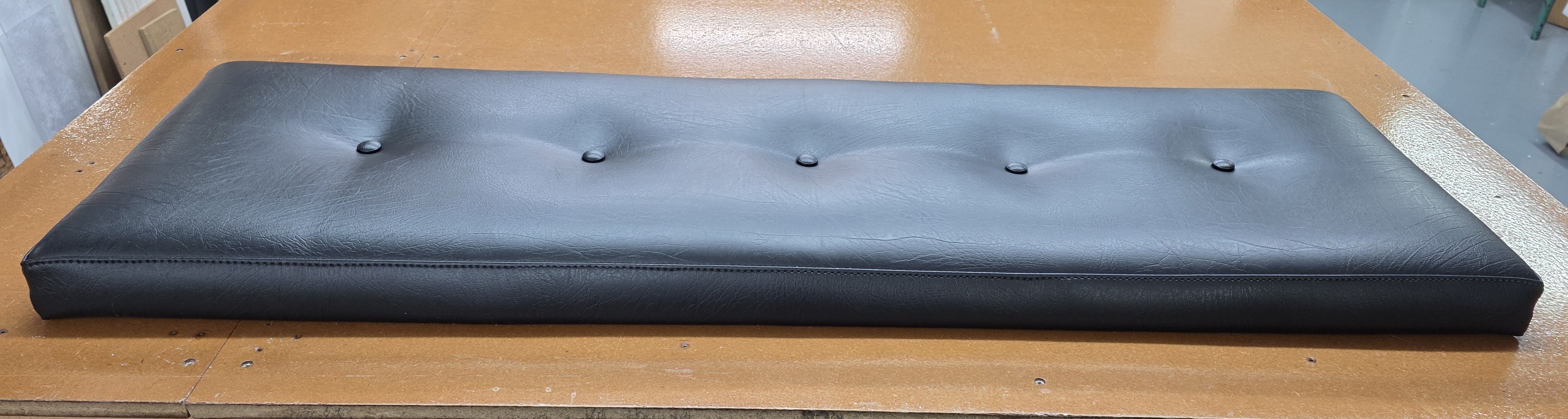 Long black button-tufted upholstered cushion